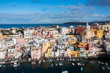 View of the Port of Corricella with lots of colorful houses on a sunny day in Procida Island, Italy.