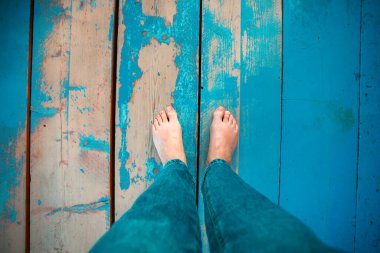 Woman leg's on wooden beach jetty. Barefeet on wooden planks. Unrecognizable person walking barefeet