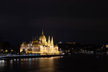 Geceleyin Budapeşte parlamento binası aydınlandı Tuna Nehri 'nde karanlık gökyüzü ve yansıması ile.
