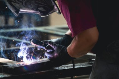 Handyman performing welding and grinding at his workplace in the workshop, while the sparks 