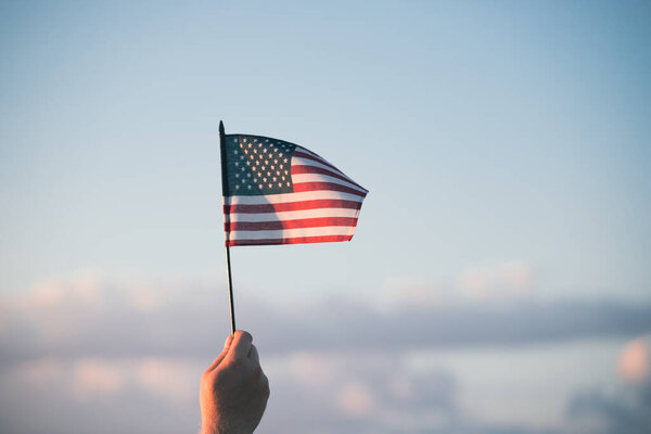 Man holding american USA flag in the sunset. Independence Day or traveling in America concept.