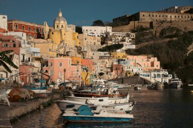 View of the Port of Corricella with lots of colorful houses on a sunny day in Procida Island, Italy.