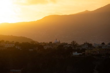 Arka planda Ischia adası olan Procida Adası üzerinde sihirli gün batımı.