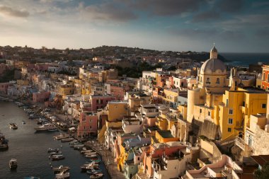 View of the Port of Corricella with lots of colorful houses in the sunset, Procida Island, Italy.