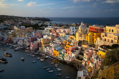 View of the Port of Corricella with lots of colorful houses in the sunset, Procida Island, Italy.