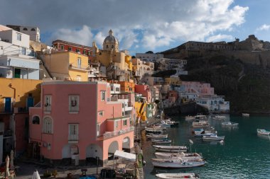 View of the Port of Corricella with lots of colorful houses on a sunny day in Procida Island, Italy.