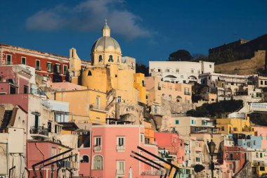 View of the Port of Corricella with lots of colorful houses on a sunny day in Procida Island, Italy.