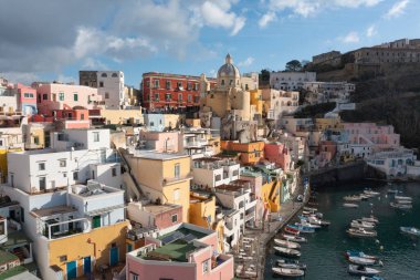 View of the Port of Corricella with lots of colorful houses on a sunny day in Procida Island, Italy.