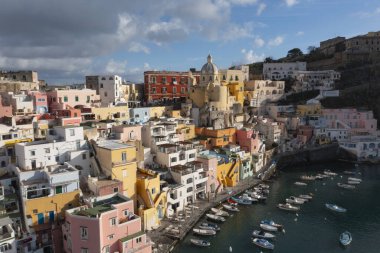 View of the Port of Corricella with lots of colorful houses on a sunny day in Procida Island, Italy.