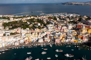 View of the Port of Corricella with lots of colorful houses on a sunny day in Procida Island, Italy.