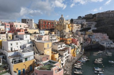 View of the Port of Corricella with lots of colorful houses on a sunny day in Procida Island, Italy.