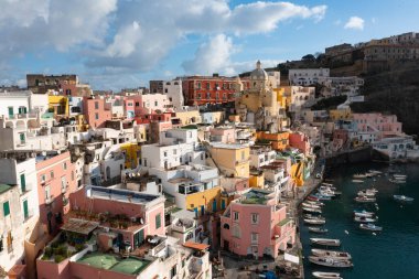 View of the Port of Corricella with lots of colorful houses on a sunny day in Procida Island, Italy.