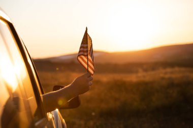 Gün batımında Amerikan bayrağı taşıyan bir adam. Bağımsızlık Günü ya da Amerika 'da seyahat.