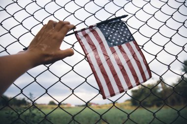 Zincirli tel örgüye bağlı bir Amerikan Bayrağı 'nı yakından çek. Amerikan göçmenlik ve ABD mülteci krizi kavramı