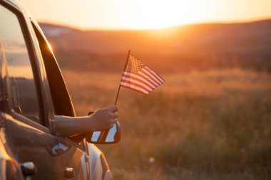 Man holding an American flag on a road trip. Independence Day or traveling in America concept.