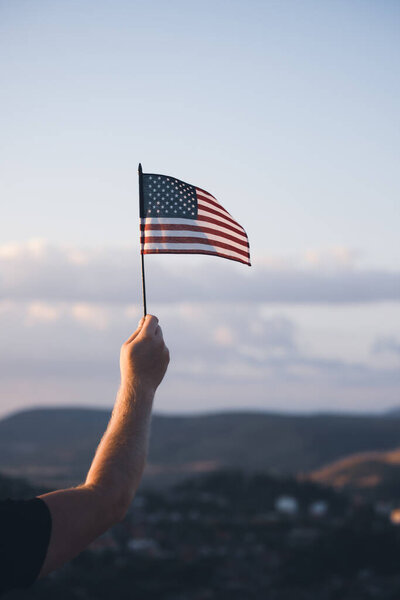 Man holding american USA flag in the sunset. Independence Day or traveling in America concept.