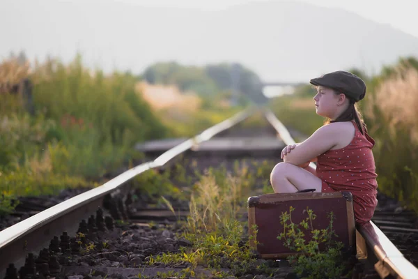 铁路上带着旧行李的小女孩的复古风格的照片 — 图库照片