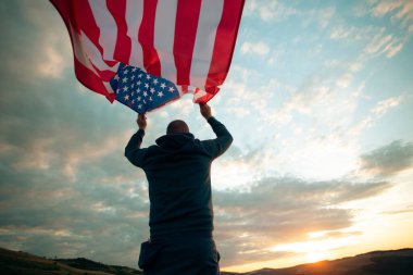 Gün batımında Amerikan bayrağı tutan adam. Bağımsızlık Günü ya da Amerika 'da seyahat.