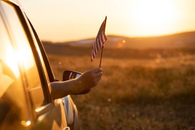 Gün batımında Amerikan bayrağı taşıyan bir adam. Bağımsızlık Günü ya da Amerika 'da seyahat.