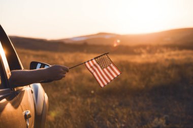 Gün batımında Amerikan bayrağı taşıyan bir adam. Bağımsızlık Günü ya da Amerika 'da seyahat.
