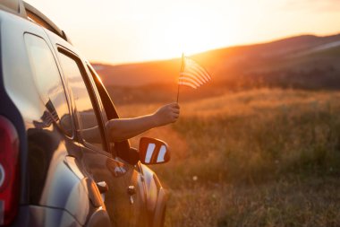 Man holding an American flag on a road trip. Independence Day or traveling in America concept.