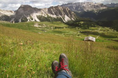 Seceda, Dolomite dağları, İtalya 'da yüksek bir dağın tepesinde oturan gezgin bacakları. Özgürlük kavramı, macera, yaz tatili aktivitesi