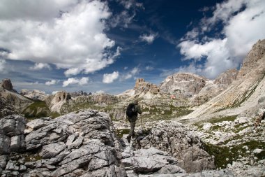 Erkek yürüyüşçü, İtalya 'nın Dolomites kentindeki Tre Cime di Lavaredo Ulusal Parkı' ndaki etkileyici zirvelerin çarpıcı güzelliğine hayran kalarak ayakta duruyor..