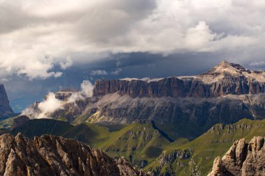 İtalya 'nın güneyindeki Marmolada' dan gelen İtalyan Dolomite 'ları dramatik fırtınalı gökyüzü ve sisli Sella grubunun panoramik görüntüsü.
