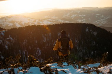 Karda yürüyen bir adam sihirli günbatımıyla kaplı bir dağda. Doğadaki aktif insanlar, macera konsepti. 