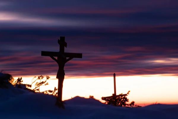 Christian wooden cross in dramatic lighting, colorful mountain sunset. Easter, resurrection concept.