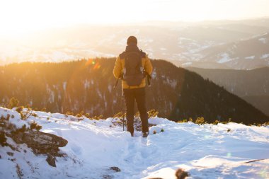 Karda yürüyen bir adam sihirli günbatımıyla kaplı bir dağda. Doğadaki aktif insanlar, macera konsepti. 