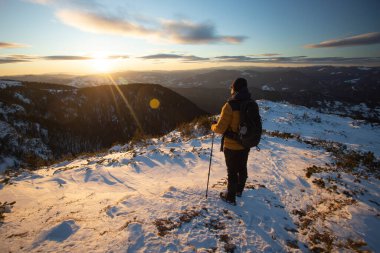 Karda yürüyen bir adam sihirli günbatımıyla kaplı bir dağda. Doğadaki aktif insanlar, macera konsepti.
