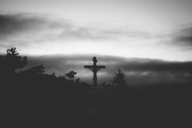 Hristiyan ahşap haçı dramatik ışıklandırmada, renkli dağ günbatımında. Paskalya, diriliş konsepti. 