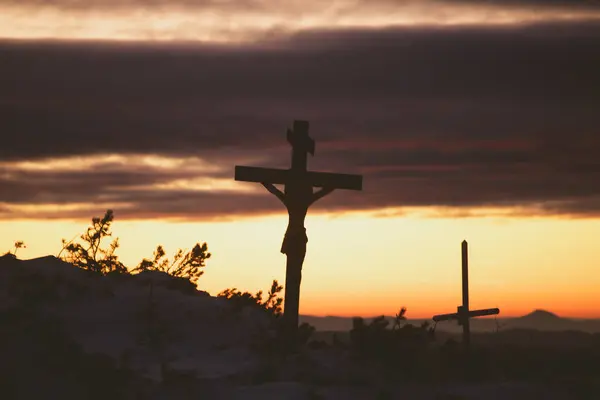 Christian wooden cross in dramatic lighting, colorful mountain sunset. Easter, resurrection concept.