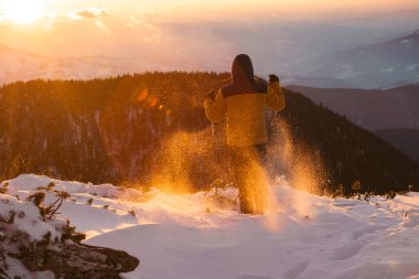 Karda yürüyen bir adam sihirli günbatımıyla kaplı bir dağda. Doğadaki aktif insanlar, macera konsepti.