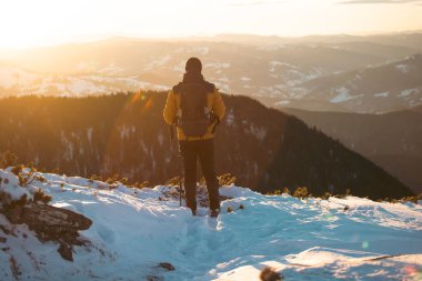 Karda yürüyen bir adam sihirli günbatımıyla kaplı bir dağda. Doğadaki aktif insanlar, macera konsepti. 