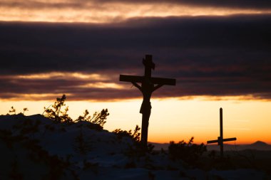 Hristiyan ahşap haçı dramatik ışıklandırmada, renkli dağ günbatımında. Paskalya, diriliş konsepti. 