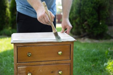 İnsan eli tebeşirle ahşap mobilya boyuyor. Yepyeni renkli tebeşir boyasıyla eski moda ahşap mobilyaları yeniliyorum. Ev dekorasyonu yeniden biçimlendiriliyor