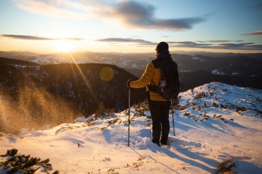 Karda yürüyen bir adam sihirli günbatımıyla kaplı bir dağda. Doğadaki aktif insanlar, macera konsepti.