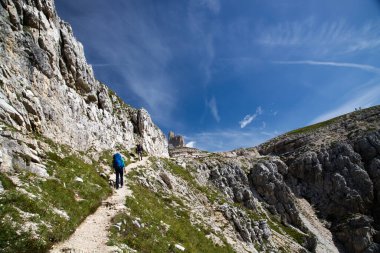 Erkek yürüyüşçü, İtalya 'nın Dolomites kentindeki Tre Cime di Lavaredo Ulusal Parkı' ndaki etkileyici zirvelerin çarpıcı güzelliğine hayran kalarak ayakta duruyor..