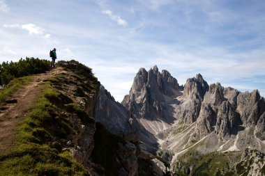 Man hiker standing and admiring stunning beauty of impressive jagged peaks of Cadini di Misurina mountain group in Dolomites, Italy, part of Tre Cime di Levaredo. clipart