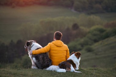 İnsan doğada köpekleriyle gün batımında.