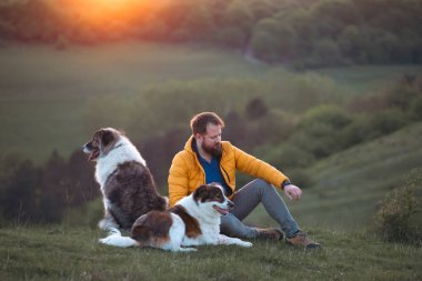 İnsan doğada köpekleriyle gün batımında.