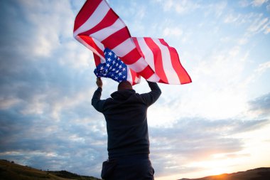 Gün batımında Amerikan bayrağı tutan adam. Bağımsızlık Günü ya da Amerika 'da seyahat.