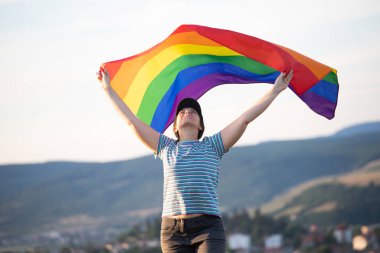 Elinde Gay Gökkuşağı Bayrağı olan bir kadın. Aynı cinsiyet çiftleri için mutluluk, özgürlük ve aşk kavramı