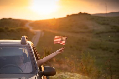 Gün batımında Amerikan bayrağı taşıyan bir kadın. Bağımsızlık Günü ya da Amerika 'da seyahat.