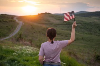 Gün batımında Amerikan bayrağını tutan kadın. Bağımsızlık Günü ya da Amerika 'da seyahat.