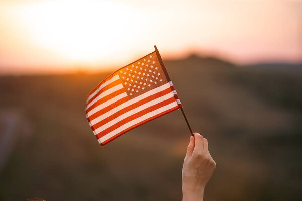 Close up on USA flag in a hand of a persone. Independence Day or traveling in America concept.