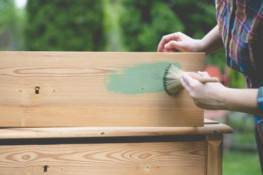 İnsan eli tebeşirle ahşap mobilya boyuyor. Yepyeni renkli tebeşir boyasıyla eski moda ahşap mobilyaları yeniliyorum. Ev dekorasyonu yeniden biçimlendiriliyor