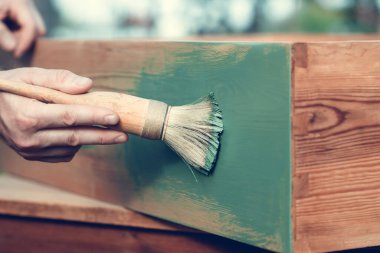 İnsan eli tebeşirle ahşap mobilya boyuyor. Yepyeni renkli tebeşir boyasıyla eski moda ahşap mobilyaları yeniliyorum. Ev dekorasyonu yeniden biçimlendiriliyor